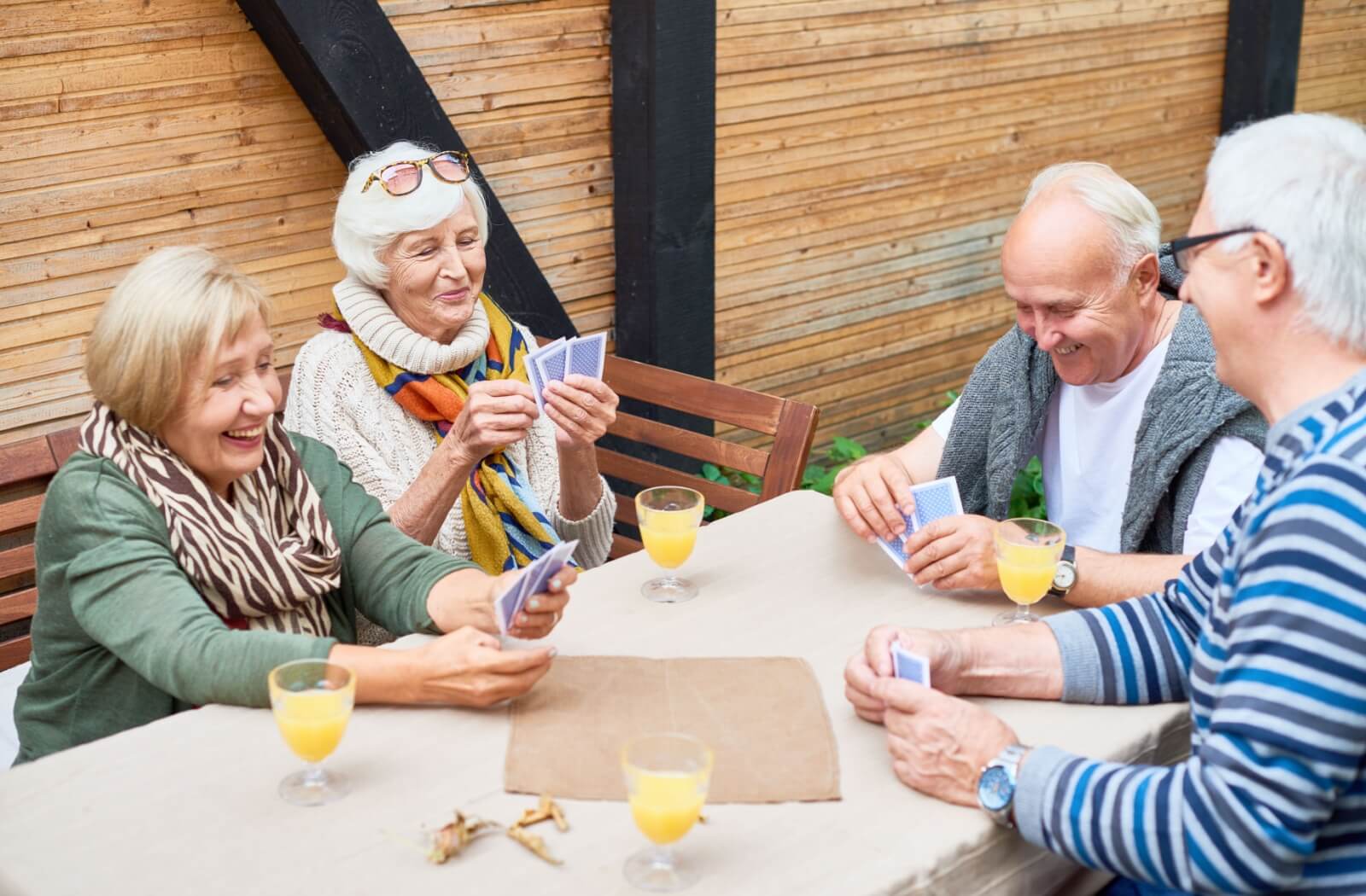 A group of older adults playing cards together outdoors.