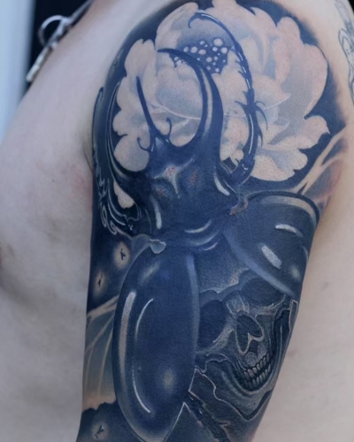 An old faded tattoo of a dragon covered with more elaborate design with multiple motifs
