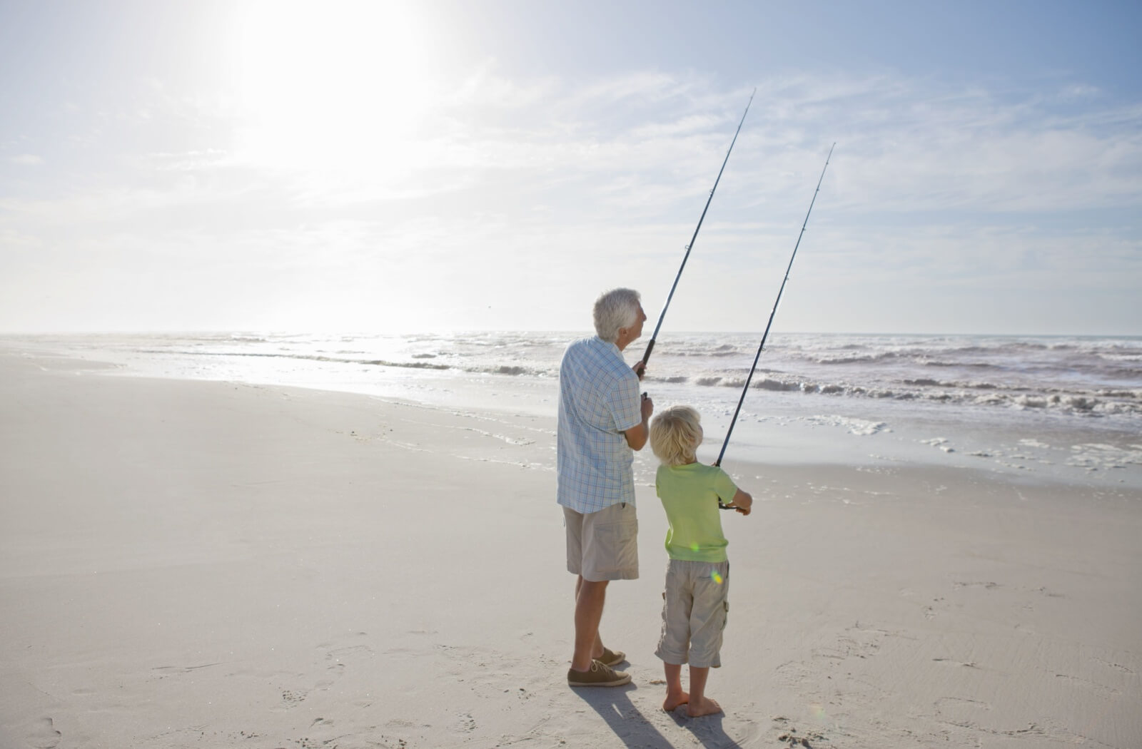 Grandparent and grandchild standing the beach fly fishing