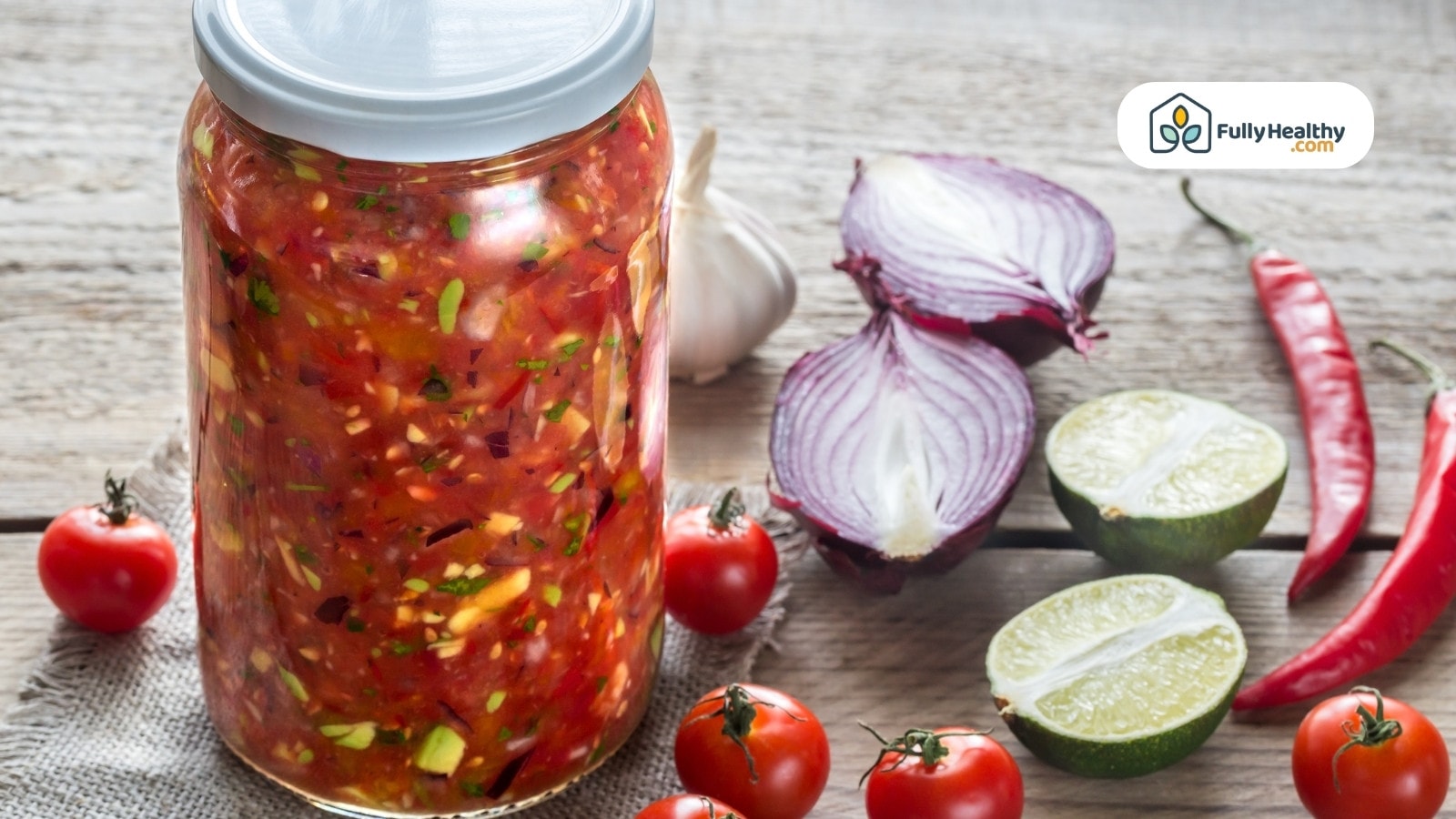 Jar of homemade salsa surrounded by fresh vegetables and spices