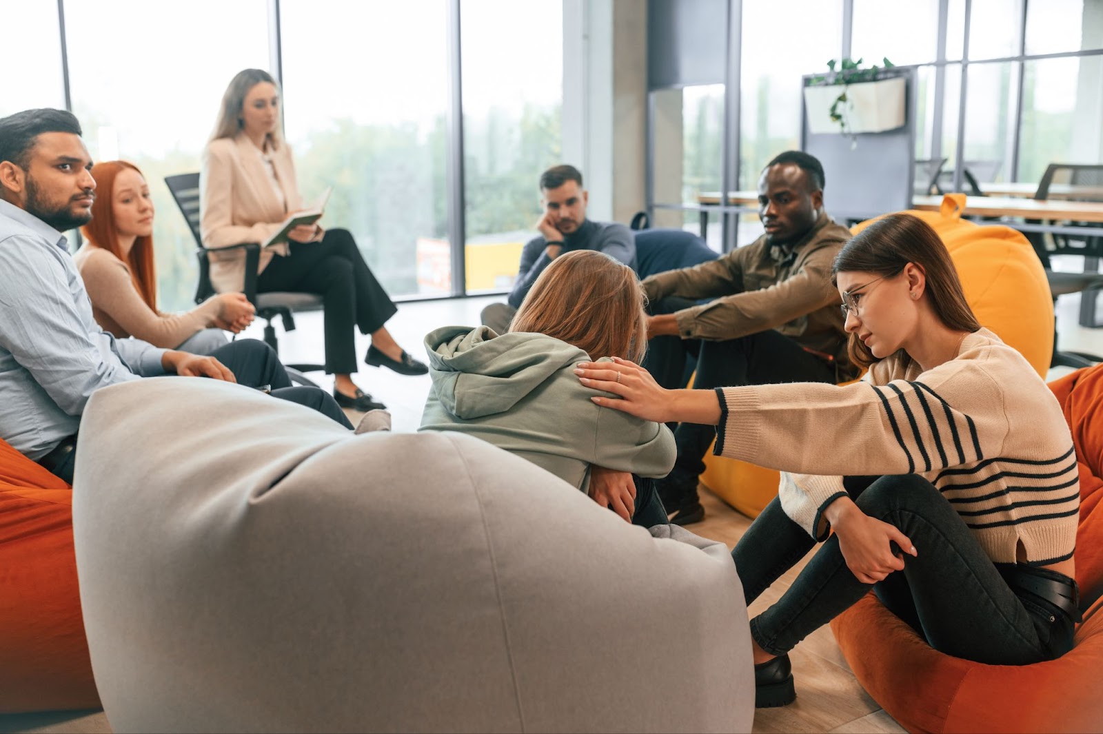 Group sitting in a circle with a therapist while comforting a girl.