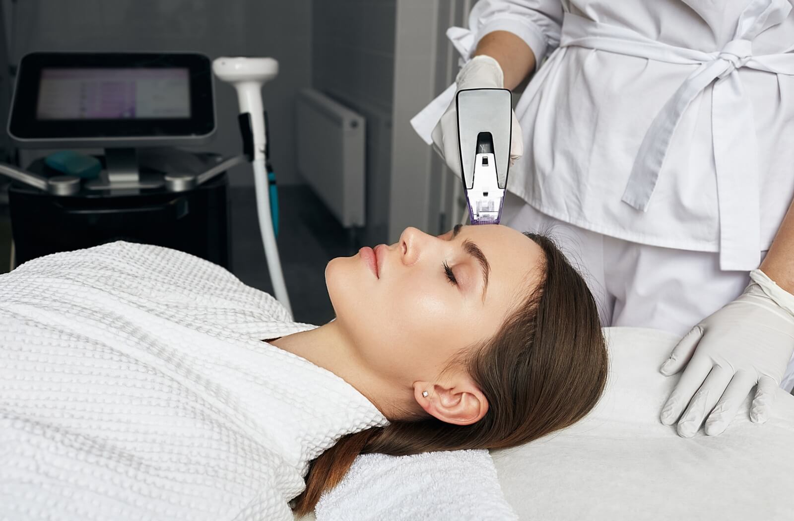 A person receives a non-invasive skin treatment on the forehead with a handheld device.