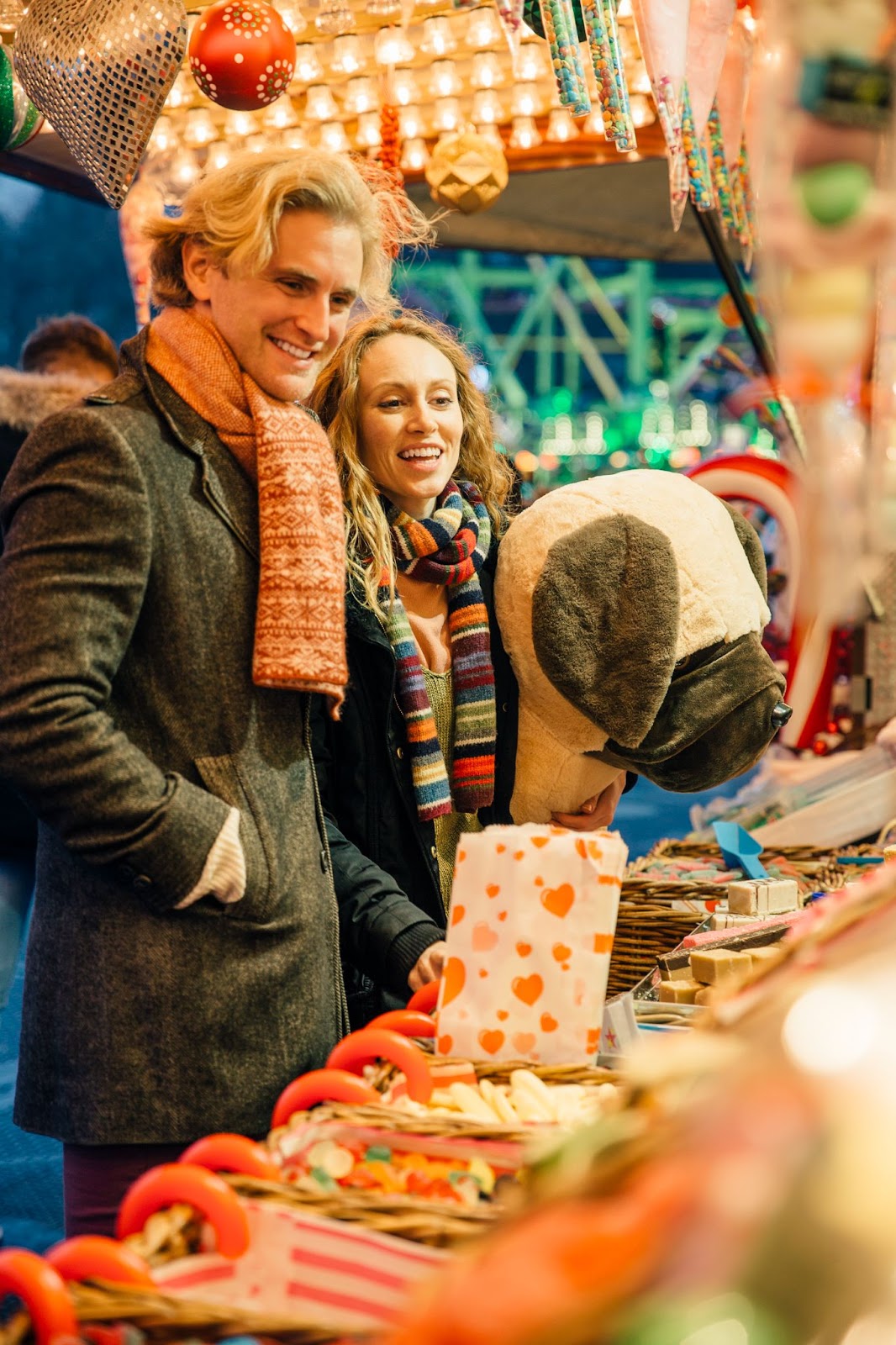 A couple enjoying the festive stalls at Hyde Park Winter Wonderland Market in London, with holiday decorations and seasonal treats