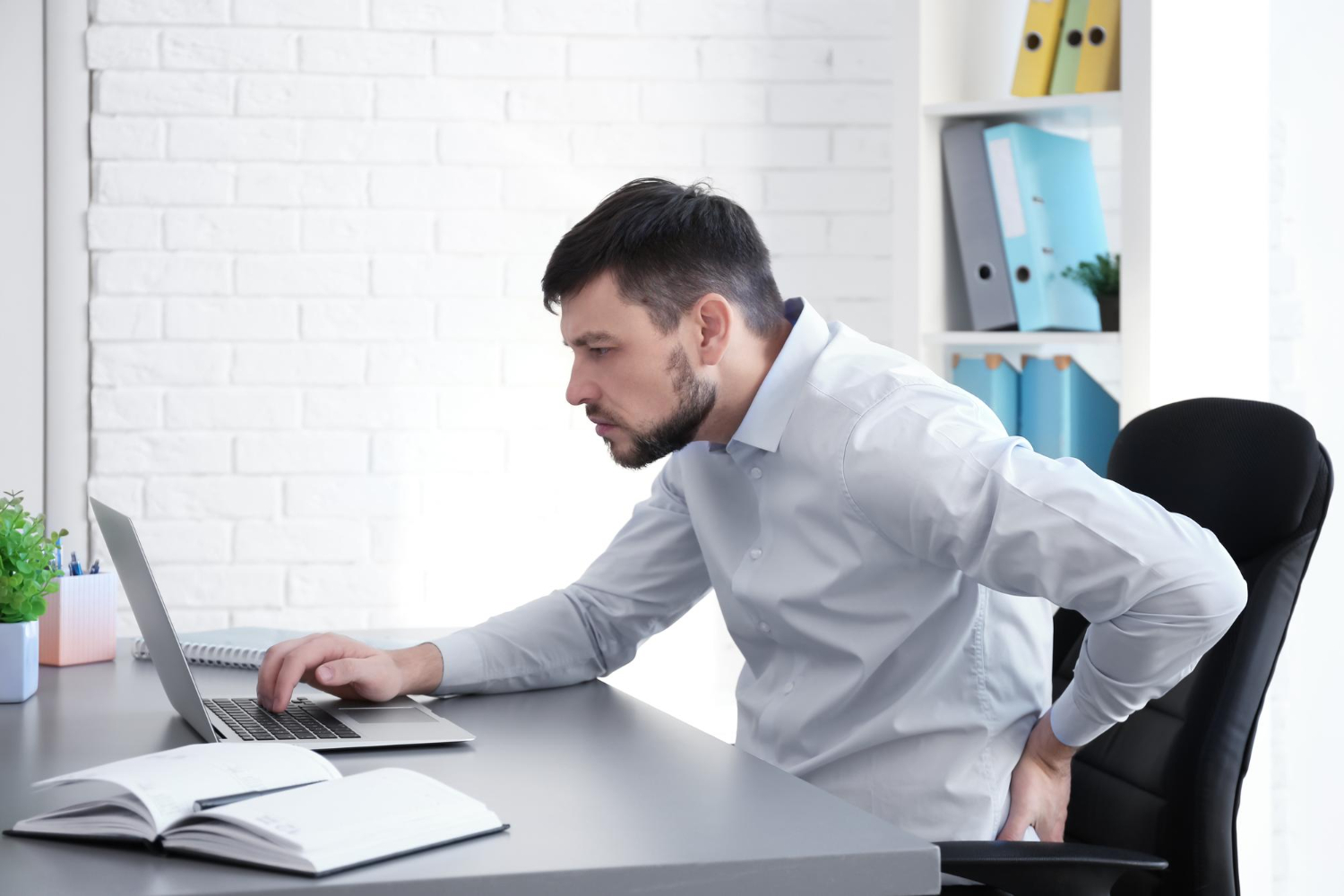 A man with poor posture at his computer, an example of risky static loading.