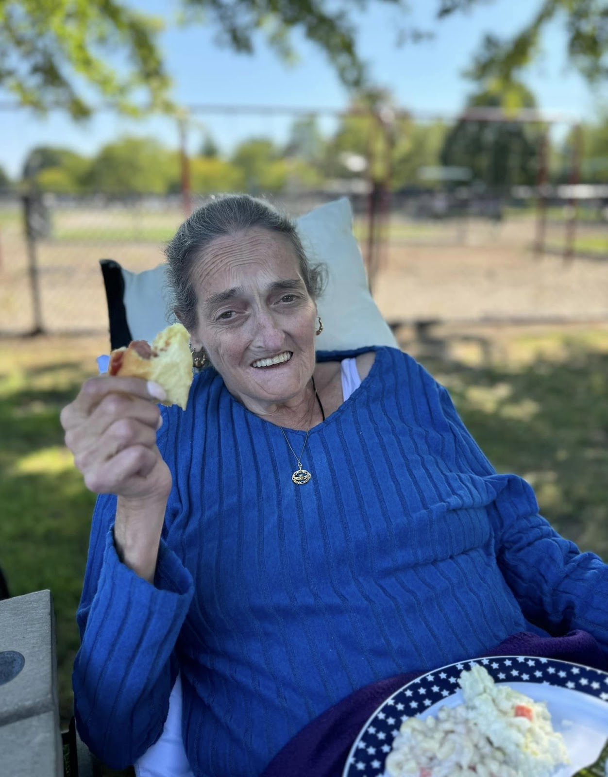 A woman smiling with a piece of a sandwich in her hand