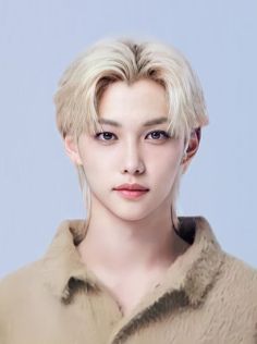 This contain Felix with blonde hair and blue eyes  in front of a gray background