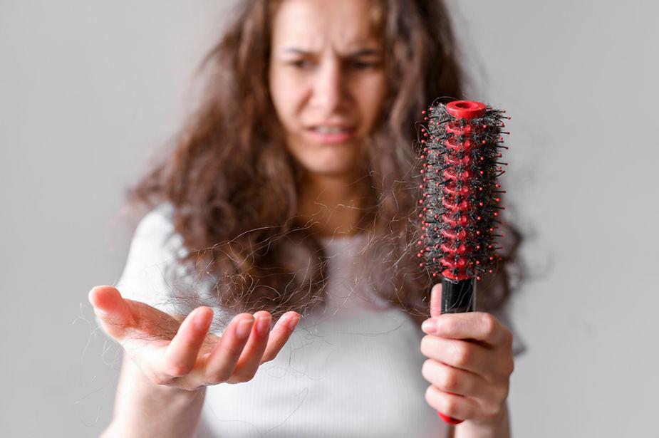 A female holding her lost hair in her hand