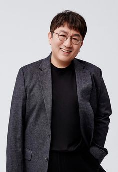 photo of Bang Sihyuk on a dark ash color suit and a black vest with a black trouser 