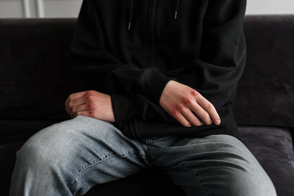 Person in Black Jacket and Blue Denim Jeans Sitting on Black Couch