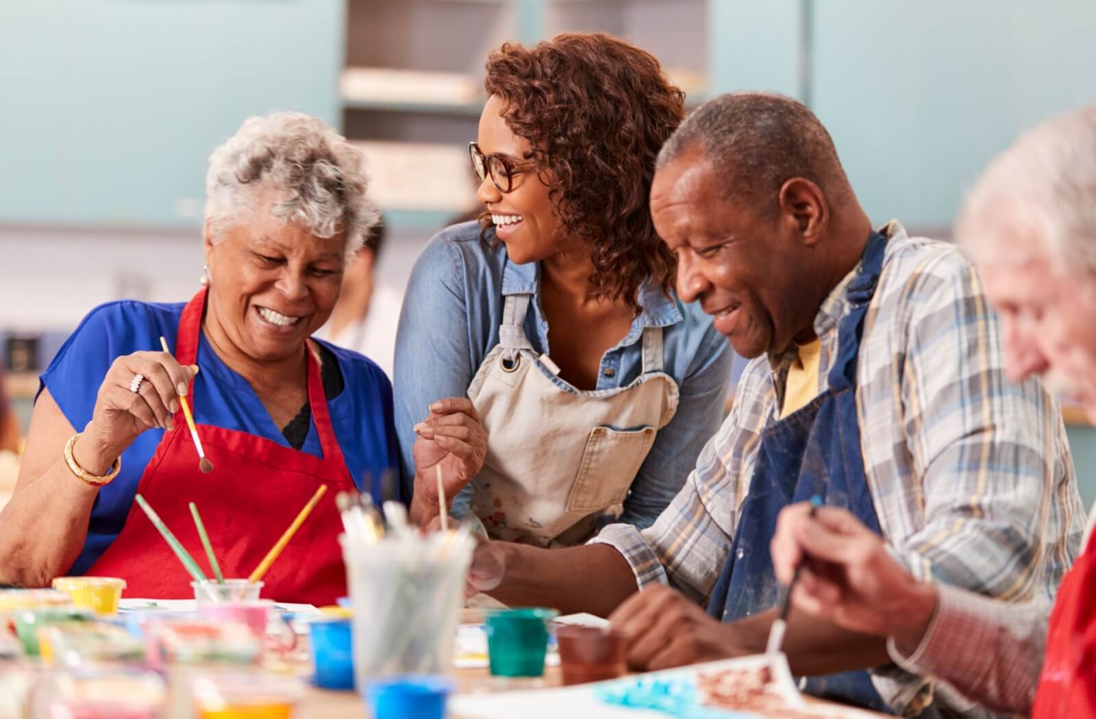 A group of older adults laughing while they do an art class in a retirement community.