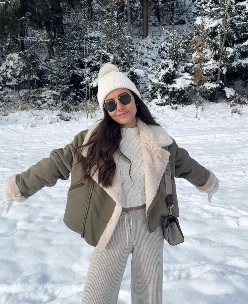 A gray faux leather and fur jacket with a white knit cap and gloves.