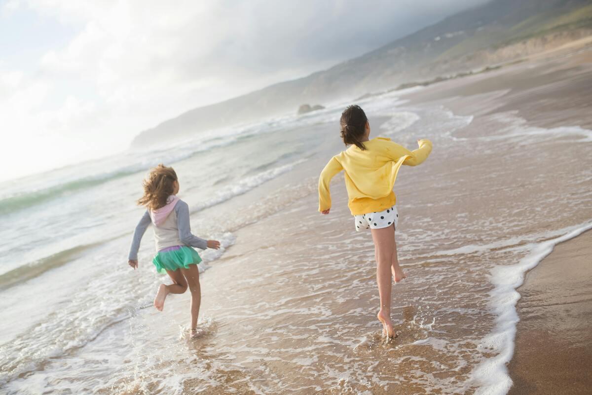 Two kids running along the seashore
