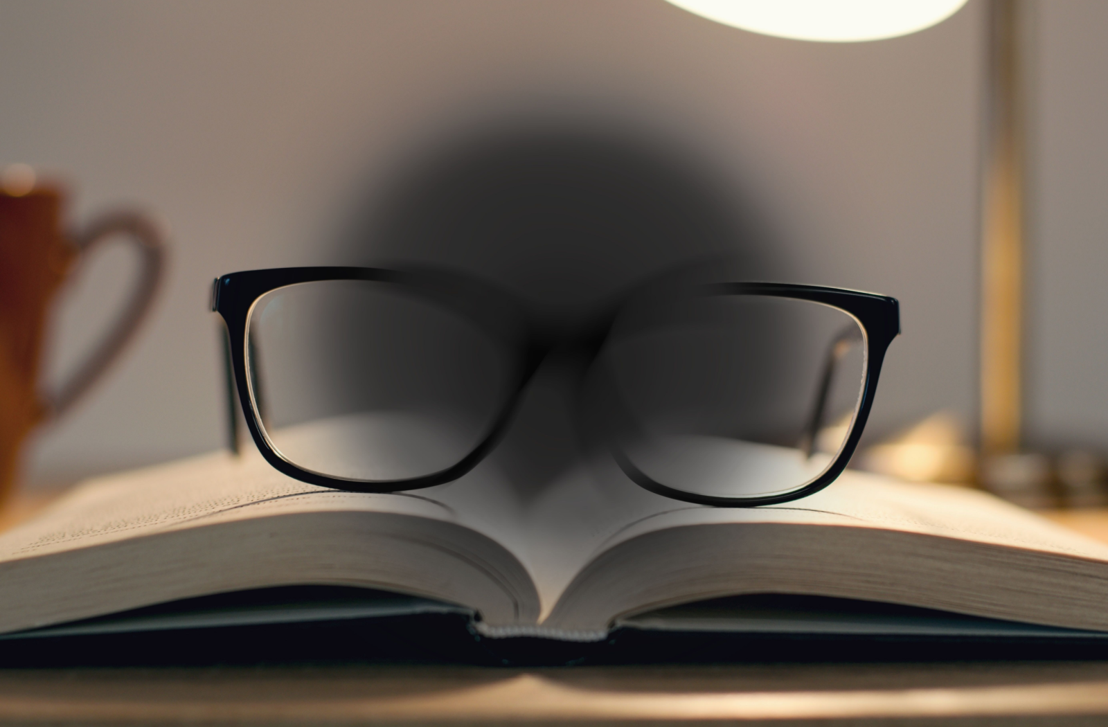 Glasses rest on a book. A gray circle distorts the image, simulating AMD.