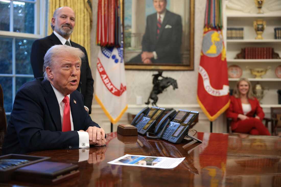 President Trump speaks to reporters as Commerce Secretary Howard Lutnick looks on in the Oval Office on Feb. 25, 2025.