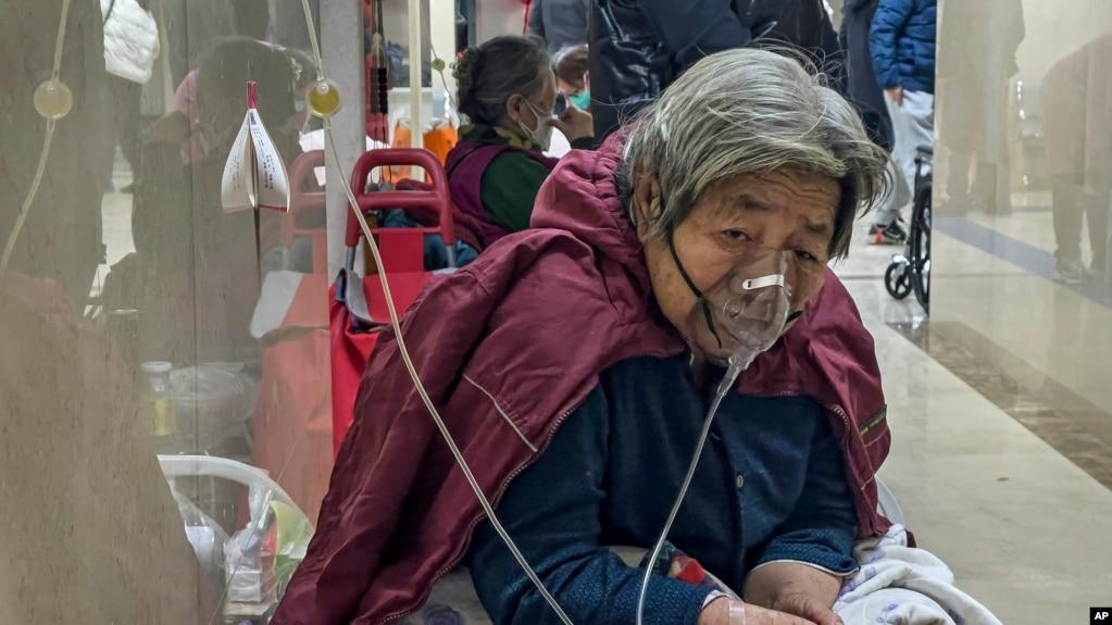 资料照片:2023年1月5日,一名老年患者在北京急诊病房走廊带着呼吸机接受静脉滴注。(美联社照片)