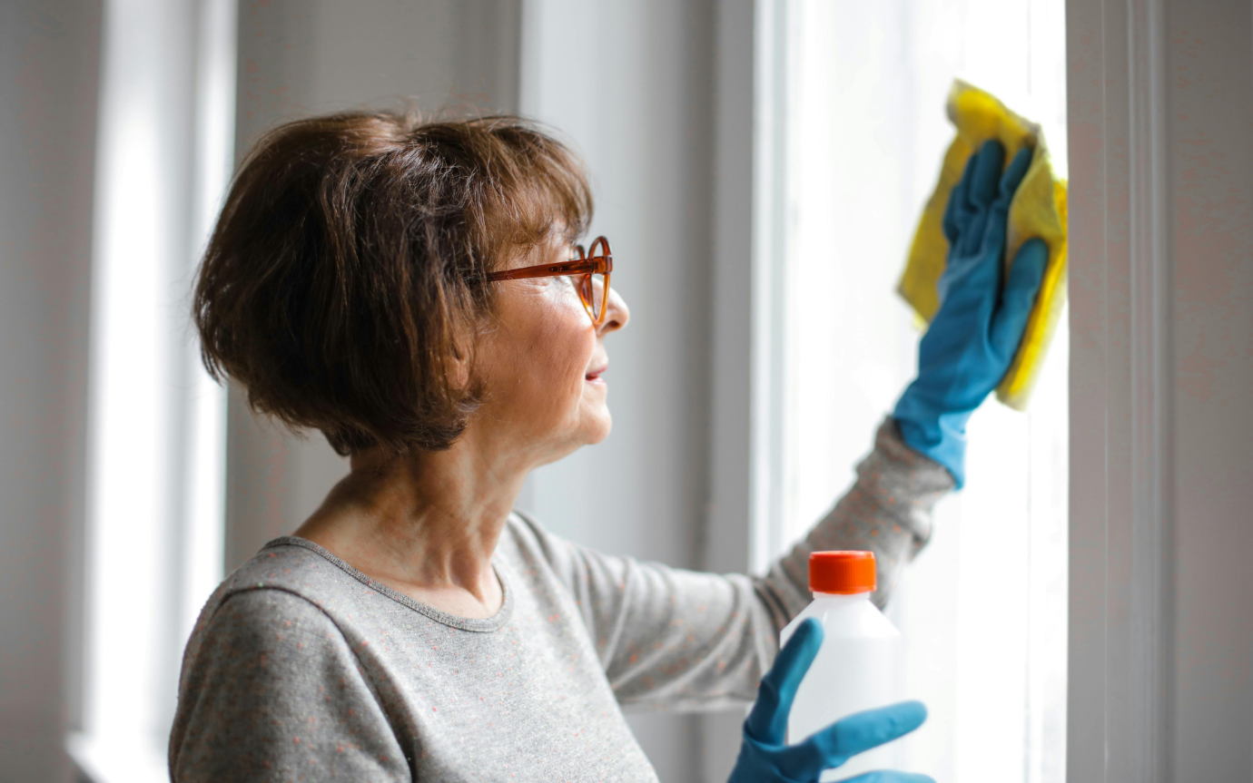 A person wearing gloves and cleaning a windowDescription automatically generated