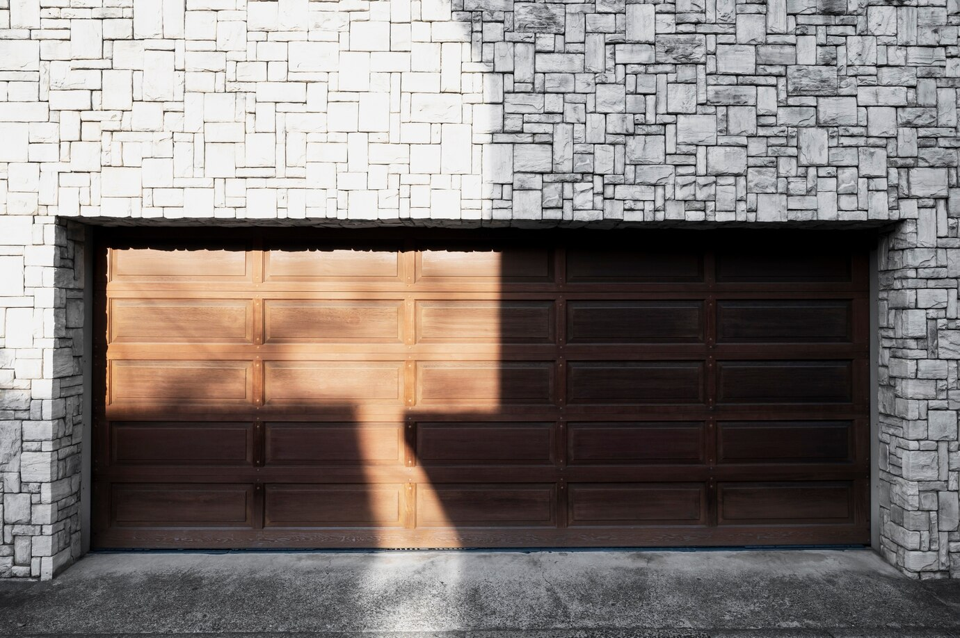 a closed wooden garage door with a stone facade around it