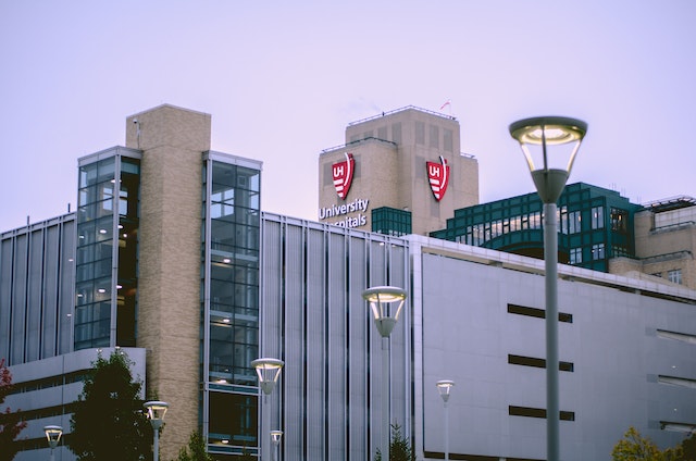 A hospital design building with glass windows and a beige facade, marked by a "University Hospitals" sign with a red logo.