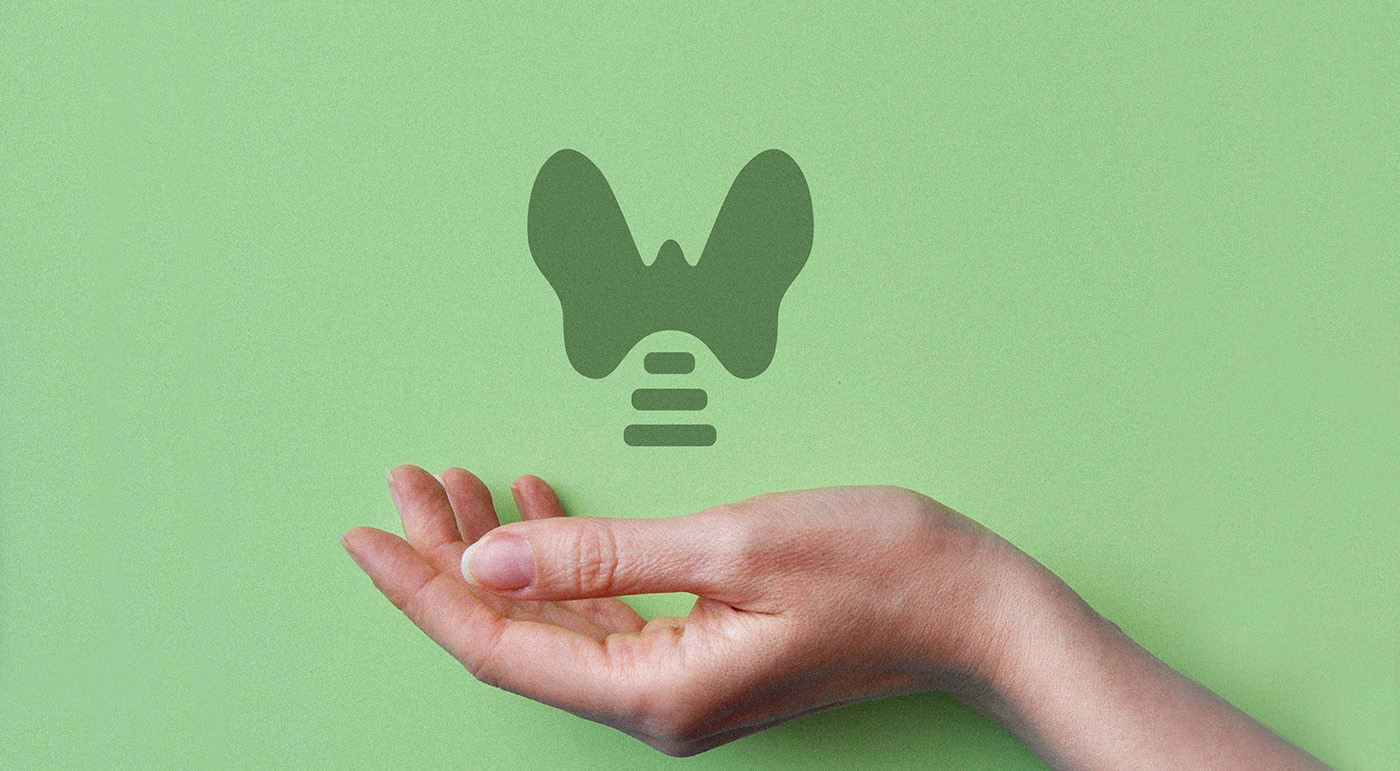 A hand holding an outline of a thyroid gland on a green background