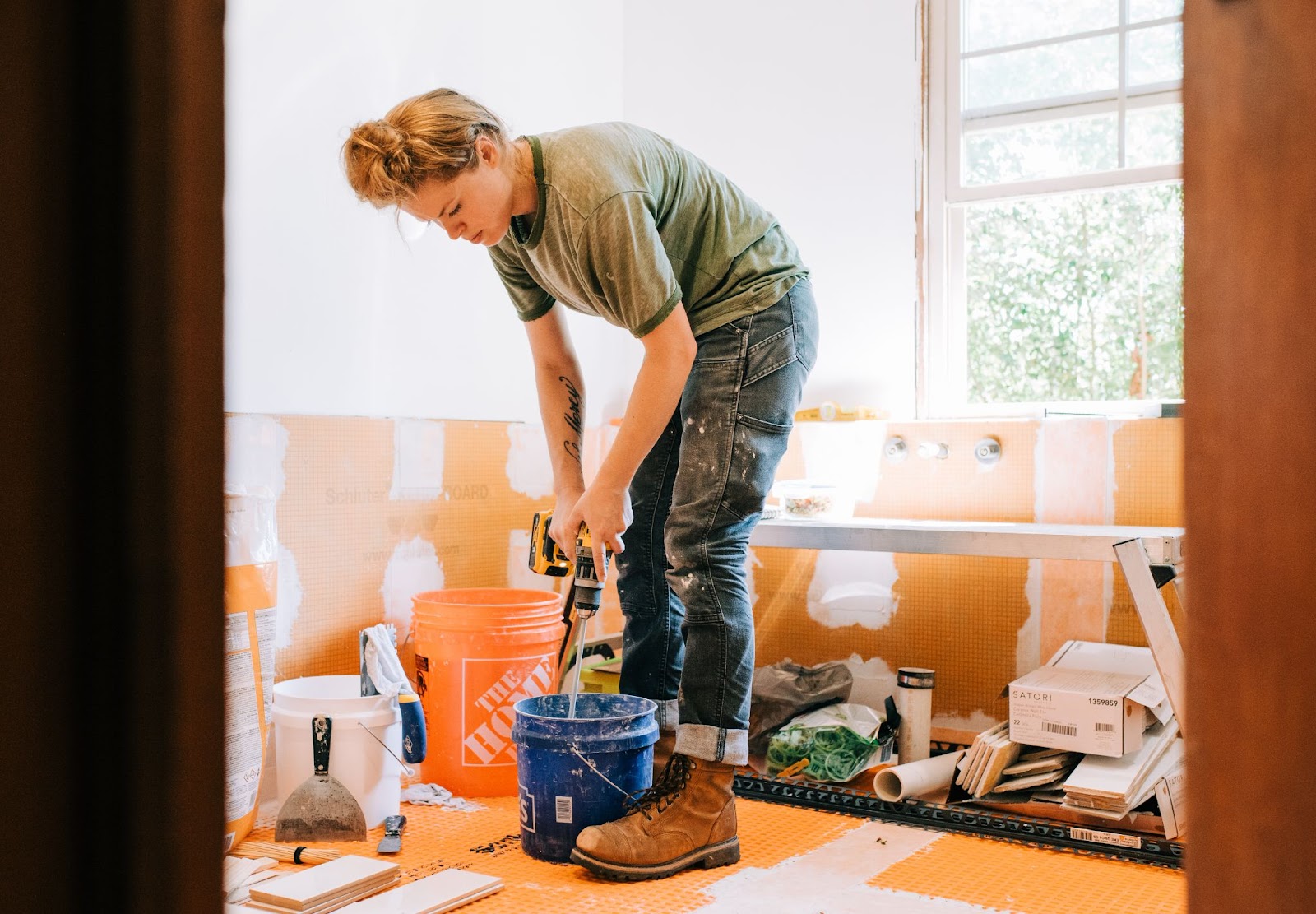 A woman actively works on bathroom remodeling tasks to transform the space.