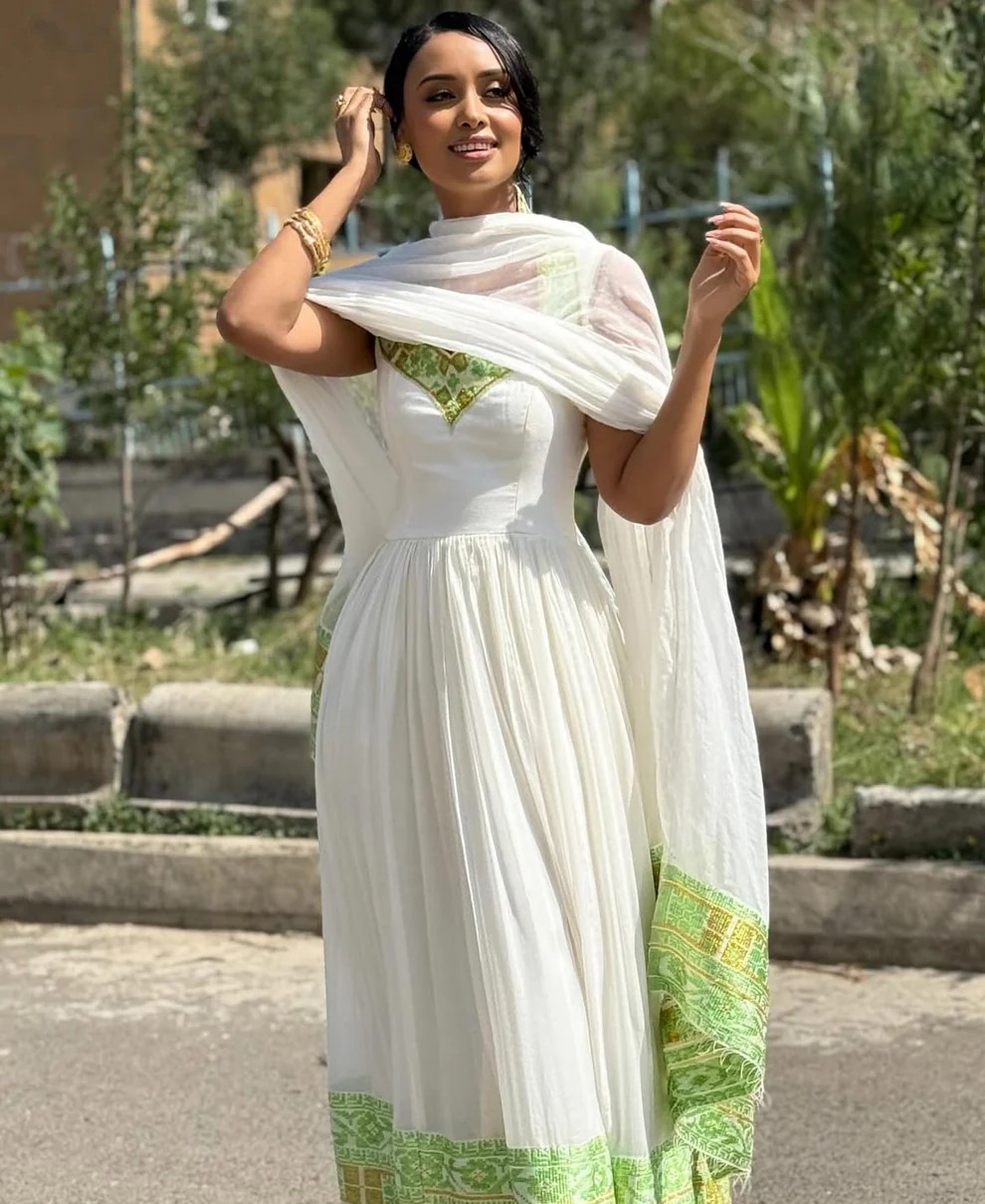 Woman in lightweight summer Habesha dress with green embroidery and matching scarf