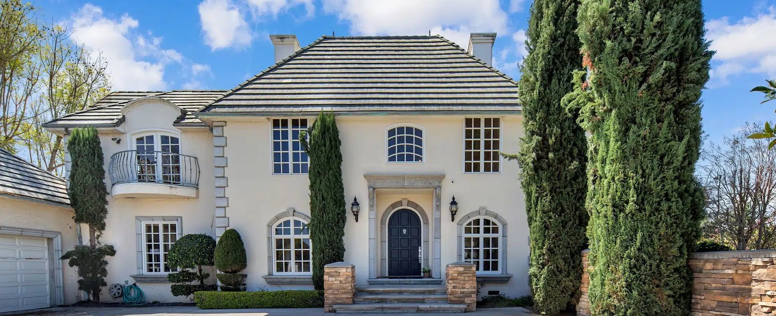  Exterior view of an AMFM facility in California, featuring a beautiful two-story building with a landscaped front yard and tall trees. 