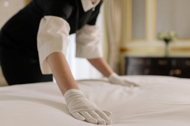 Hotel employee cleaning a bed, example of hotel pest control