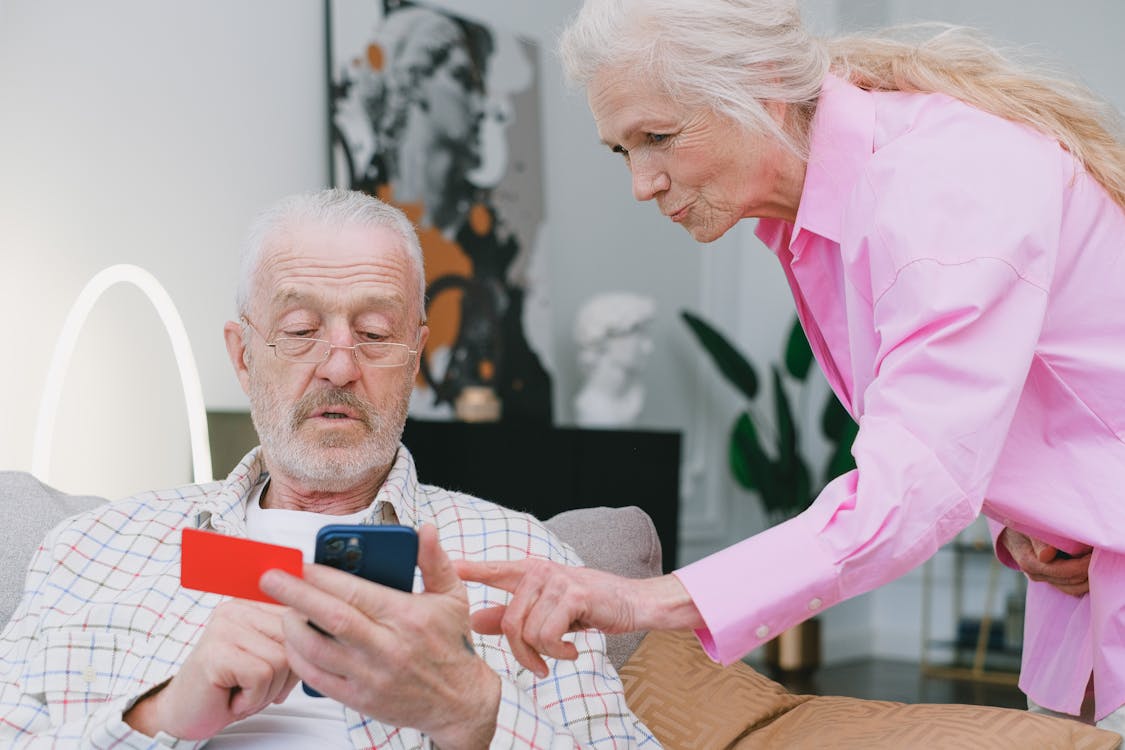 Free Elderly couple handling credit card transaction on smartphone indoors. Stock Photo