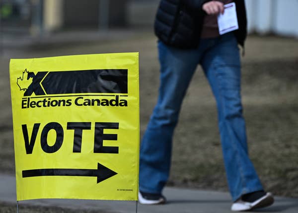 Person walking past a &quot;Vote&quot; sign for Elections Canada, indicating a polling station location