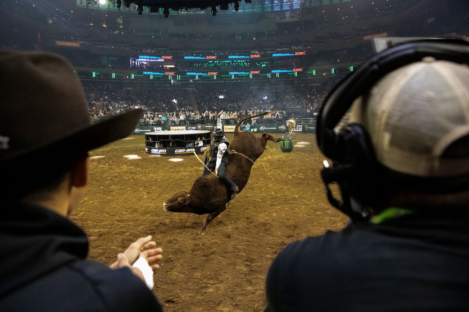 Brown bull kicks high in the air, but the rider stays on.