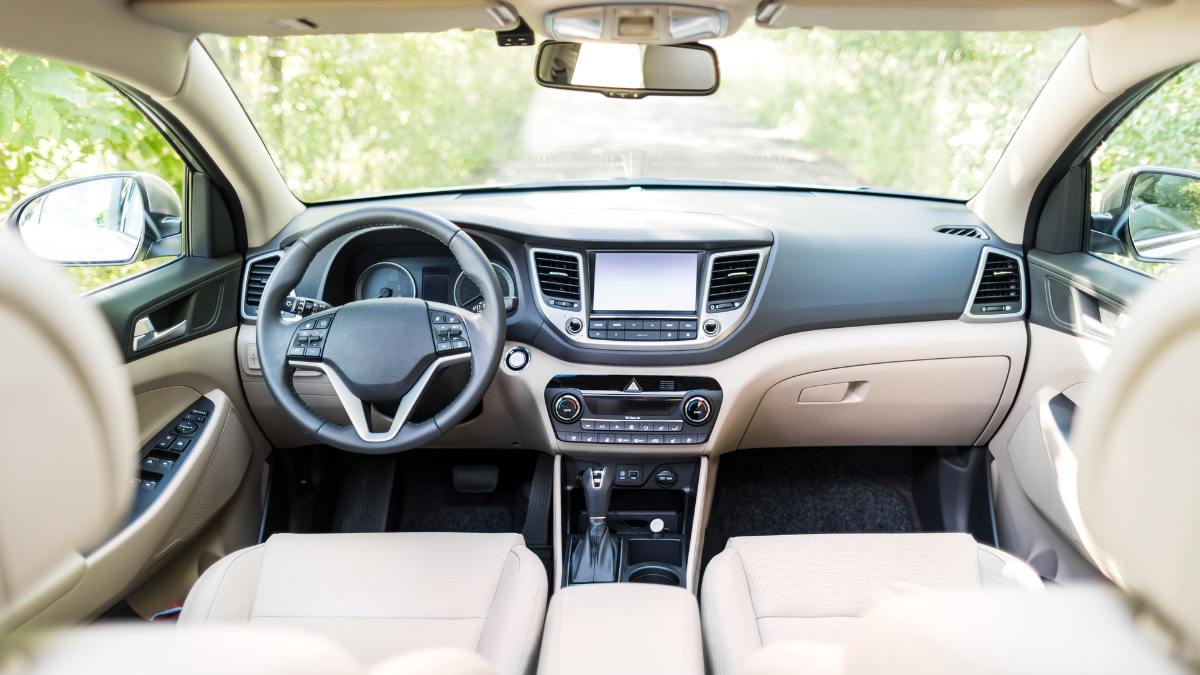 This image shows a sleek car interior with a modern dashboard, multifunctional steering wheel, touchscreen display, and beige leather seats, highlighting elegance and spaciousness.