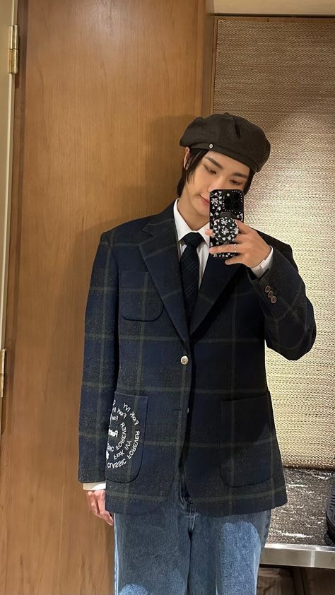 This contains an image of ATEEZ Seonghwa's taking a selfie in front of a mirror wearing a suit and hat