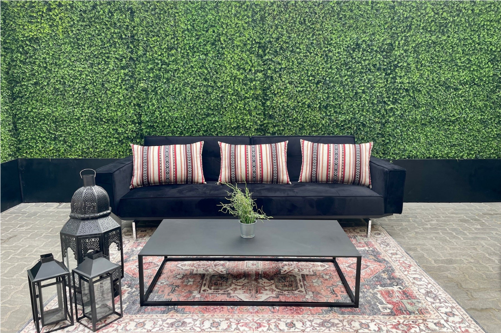 Styled wedding venue setup with black velvet sofa, patterned cushions, lanterns, and Persian-style rug.