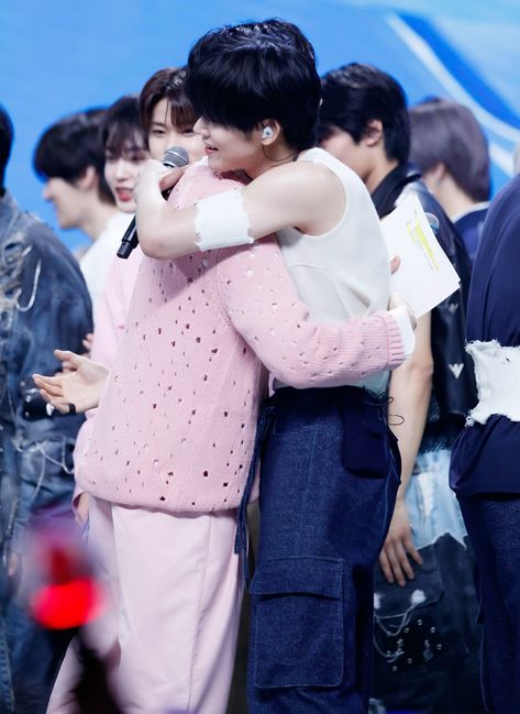 This contains an image of ZEROBASEONE Hanbin and TXT Yeonjun hugging each other