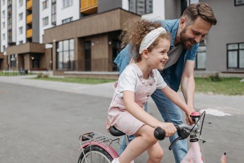 Free Girl Learning How to Ride a Bicycle with her Dad Stock Photo