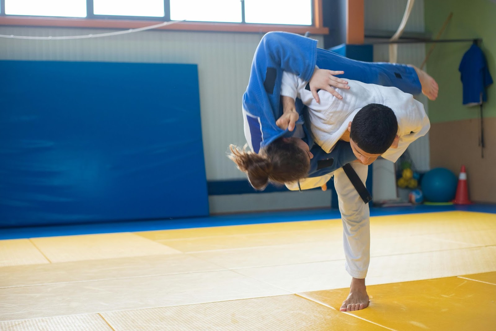 Two martial arts practitioners in the middle of a leg-sweep takedown