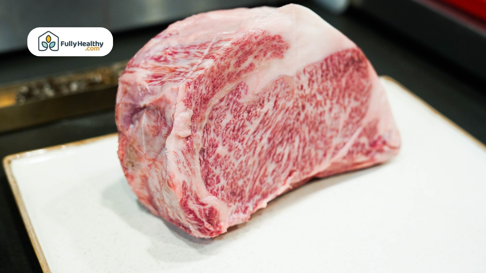 Large raw Wagyu beef cut with heavy marbling on plate