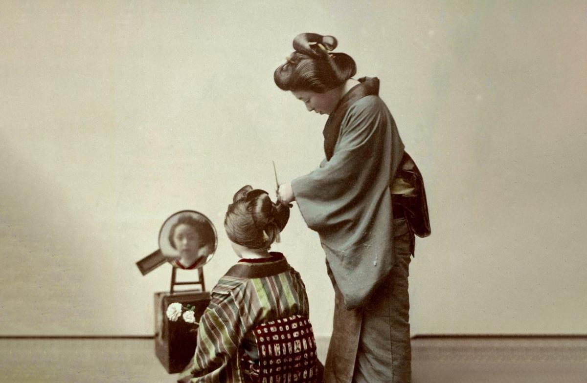 A photo of a Geisha fixing the hair of another Geisha. Photo via Okinawa Soba.