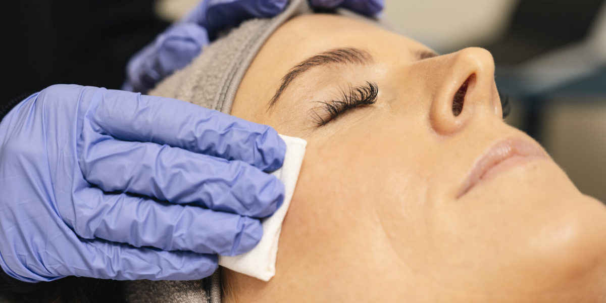 A woman receiving a facial treatment in a salon, focusing on personalized skincare with Hydrafacial technology.