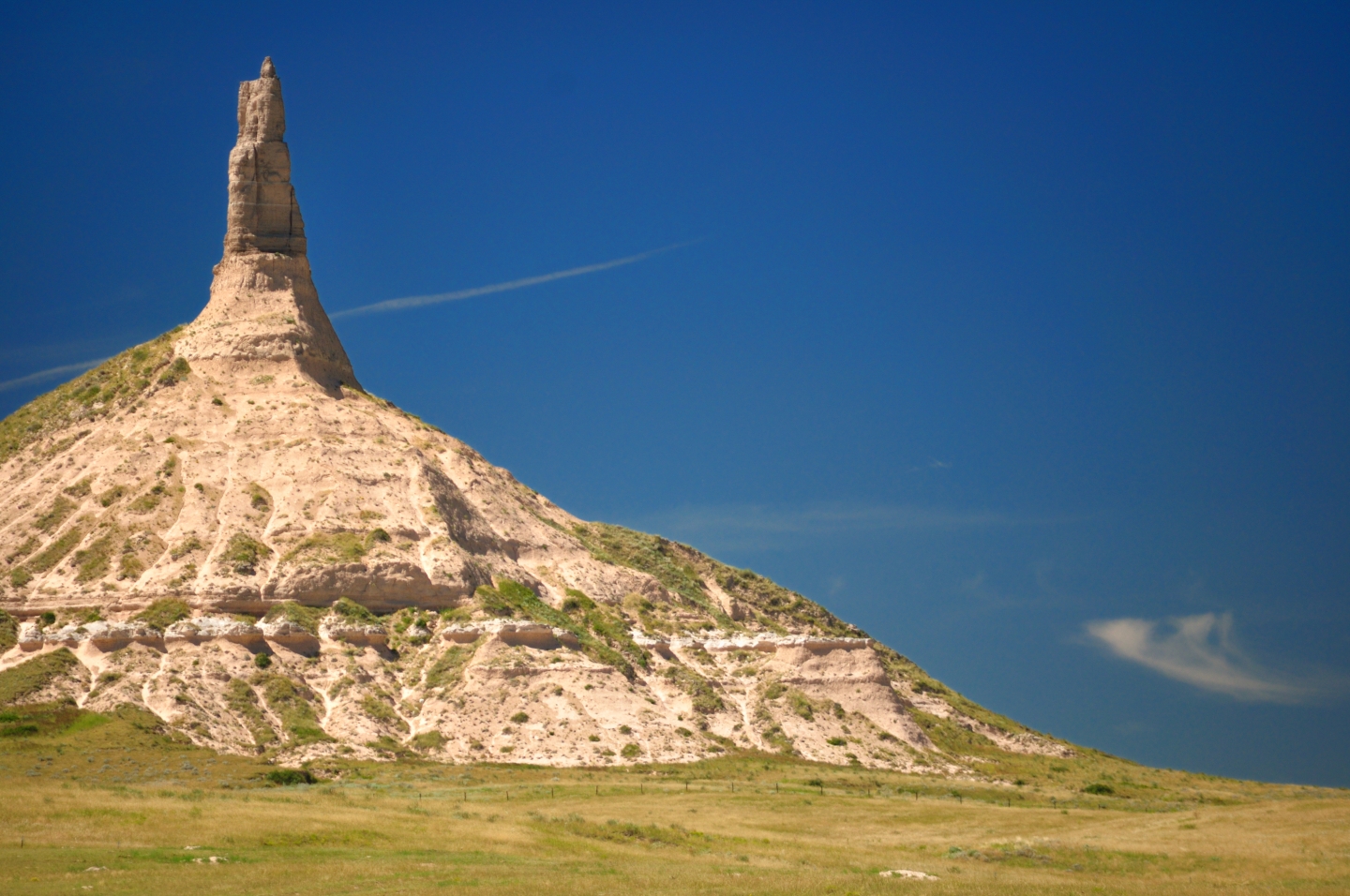 Chimney Rock with a lush green park in the foreground and a clear sky above.