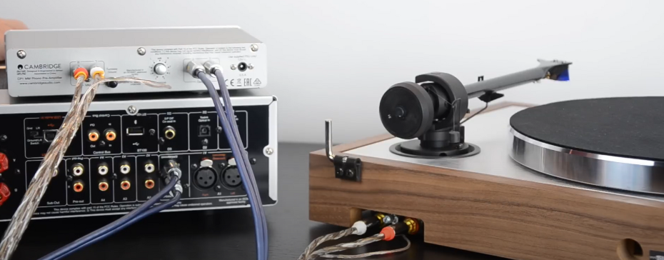 Turntable connected to a Cambridge audio preamp and other audio equipment with various cables.