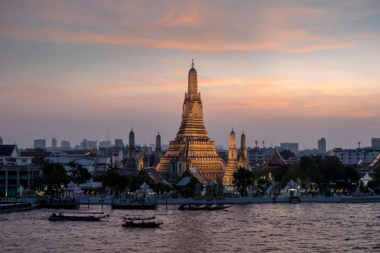 A large building with Wat Arun and a body of water

Description automatically generated