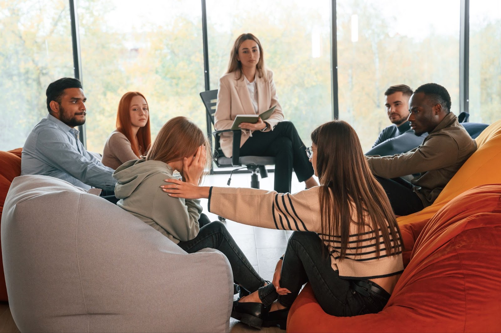 Attendees of a therapy group share their stories and show their support for a member who cries while sharing hers.