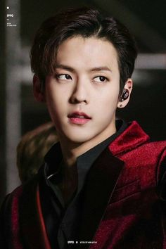 This contains an image of Minhyuk wearing a  black and red jacket with an ear pod in his ear