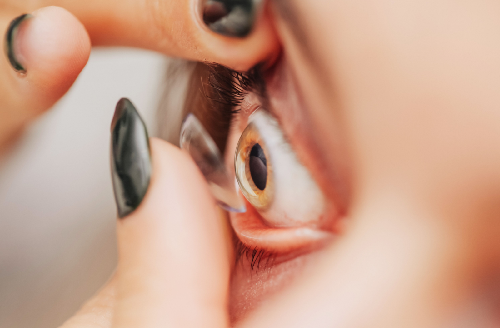 A close shot of a person inserting a contact lens into their eye.