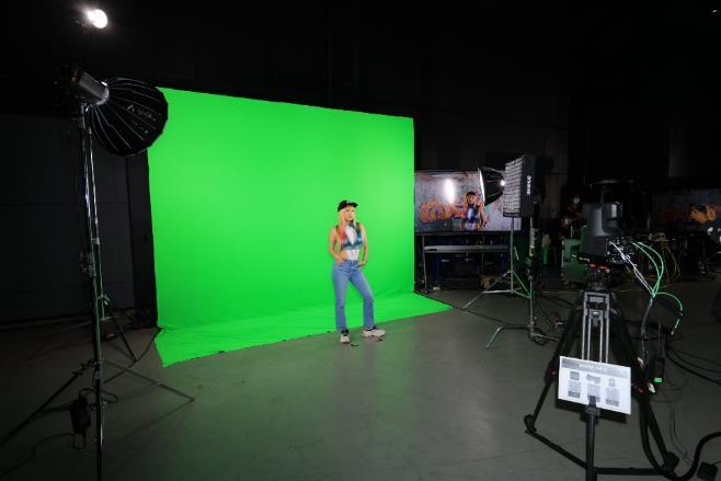 A person singing in front of a green screen

Description automatically generated