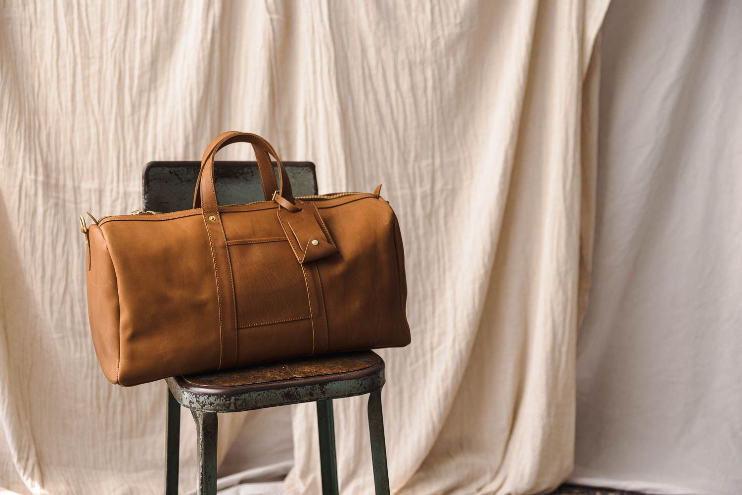 A PanAm Duffle Bag from WP Standard placed on a black chair with a white cloth as a backdrop.