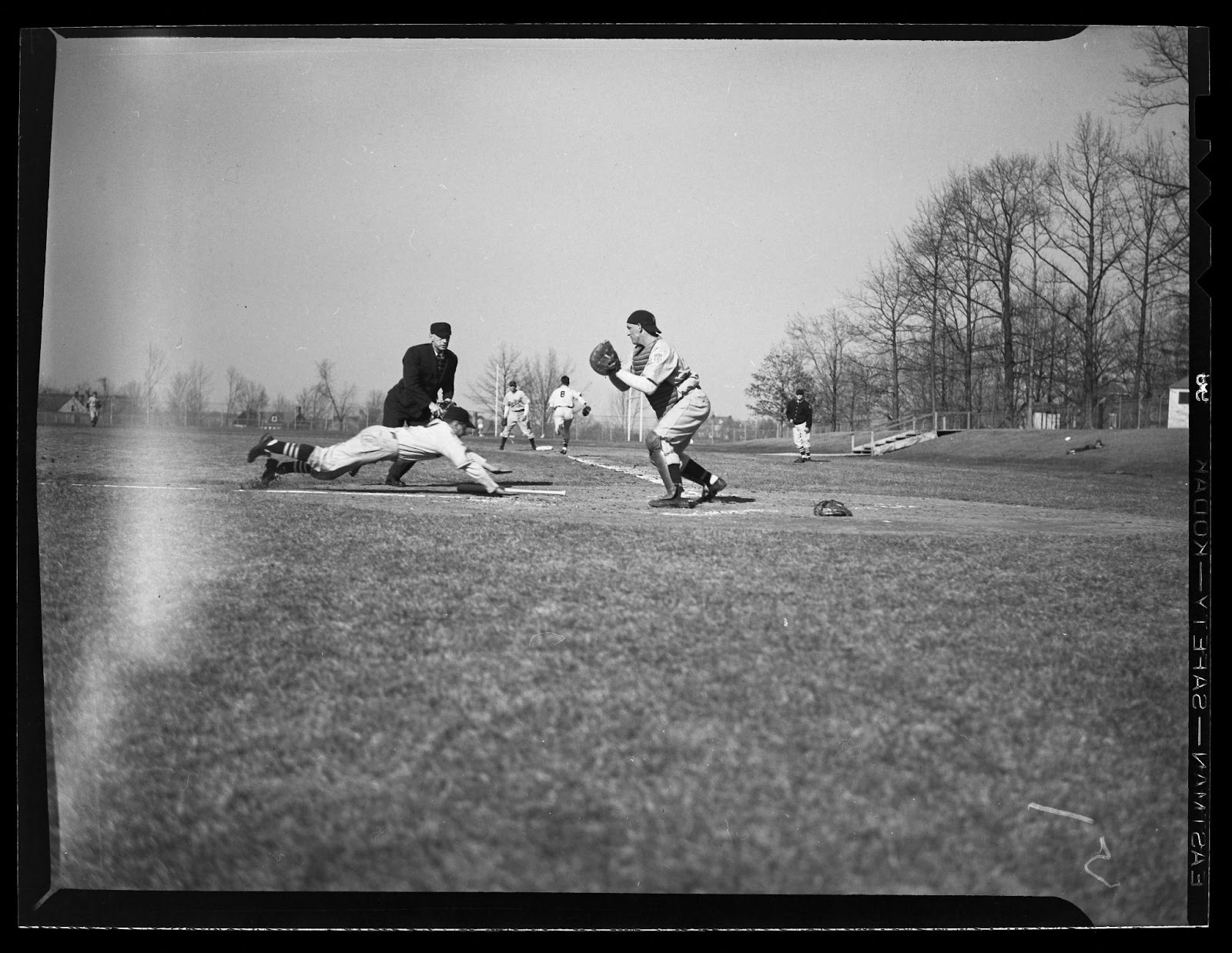 A baseball playing diving for a base with the baseman getting ready to tag him