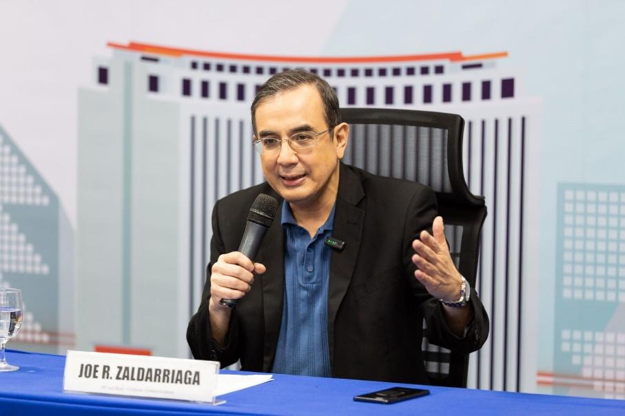 A person sitting at a table talking into a microphone

Description automatically generated