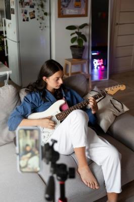 Full shot girl playing the guitar indoors